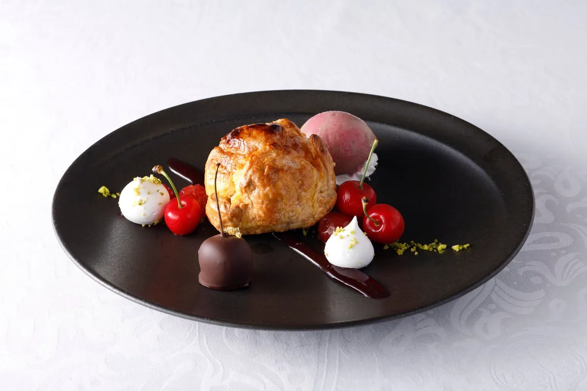 温かいチェリーパイにフレッシュなさくらんぼとアイスが添えられた一皿