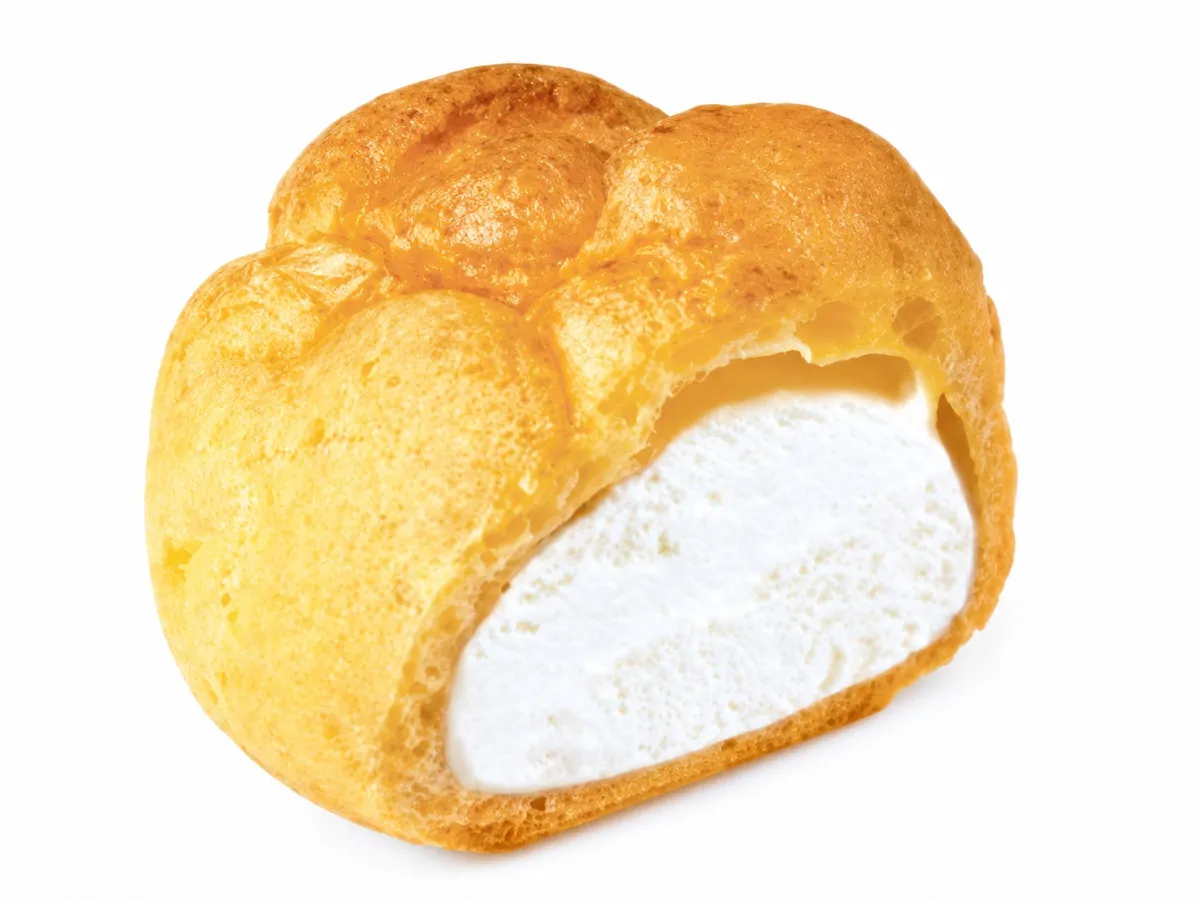 白いミルキークリームがぎっしり詰まった、こんがり焼き色のシュークリームの断面