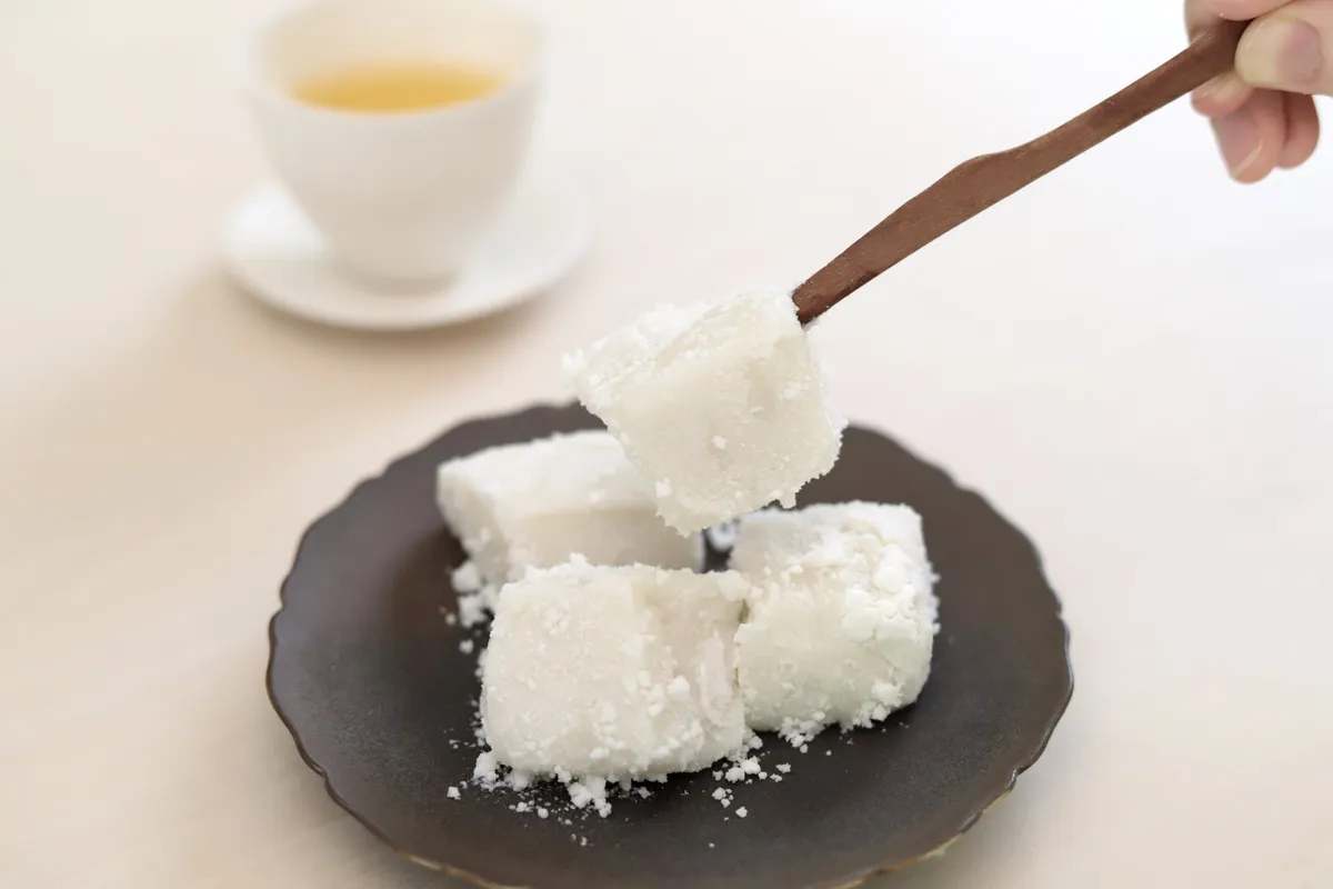 木製の菓子切りで持ち上げた、ココナッツを纏った真っ白なわらび餅