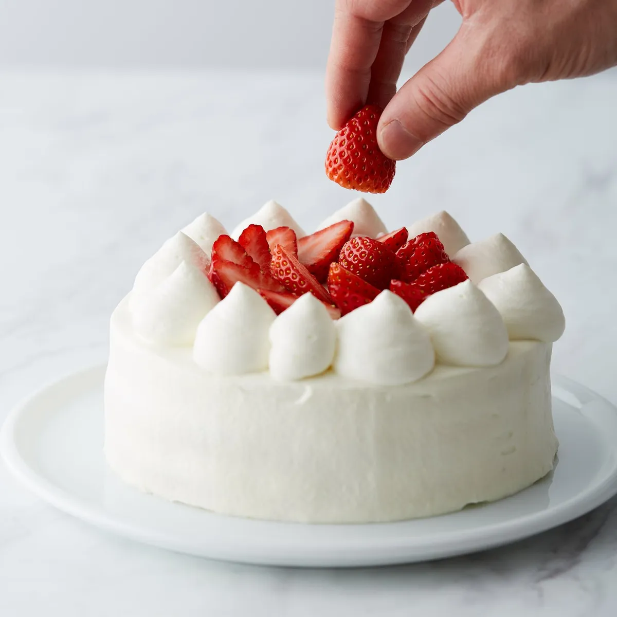 ケーキに苺をトッピングするパティシエの手元