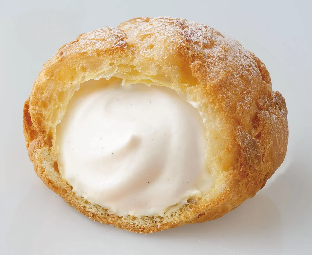 バニラヨーグルトのカップと並んだ、粉糖がかかった美味しそうなシュークリーム