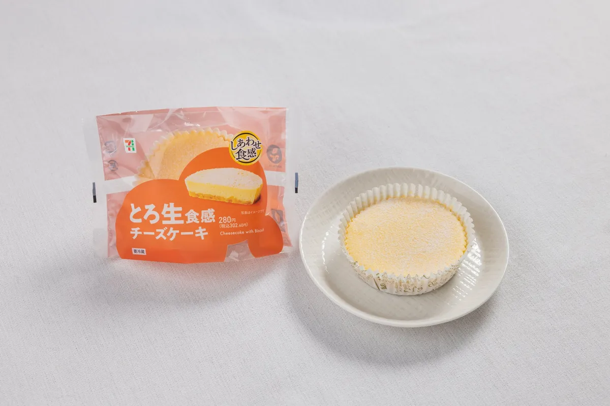 シンプルな背景に置かれた、セブン‐イレブンのとろ生食感チーズケーキのパッケージと中身