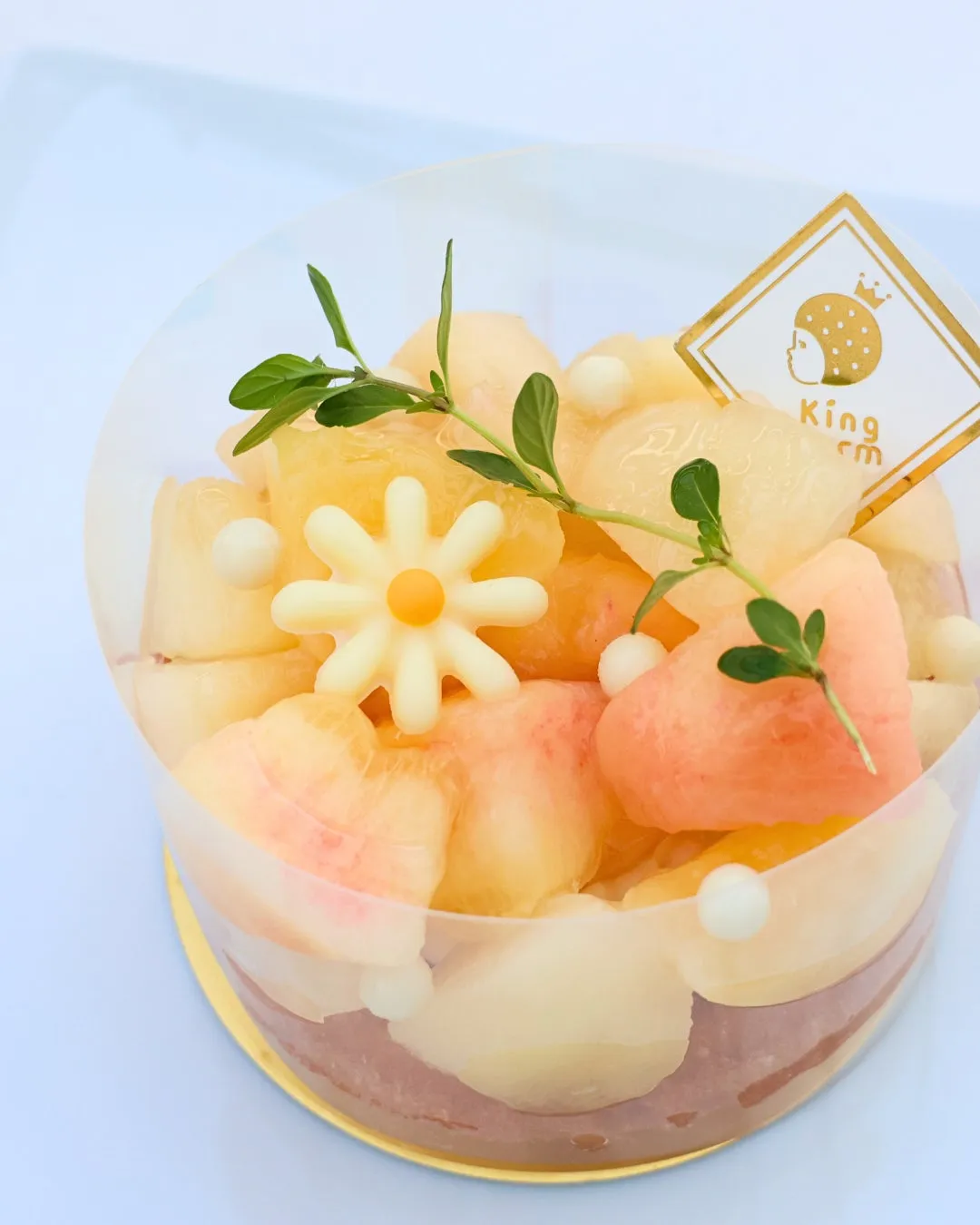 チーズバウムの上にカットされた桃とお花のチョコレートが乗ったスイーツ