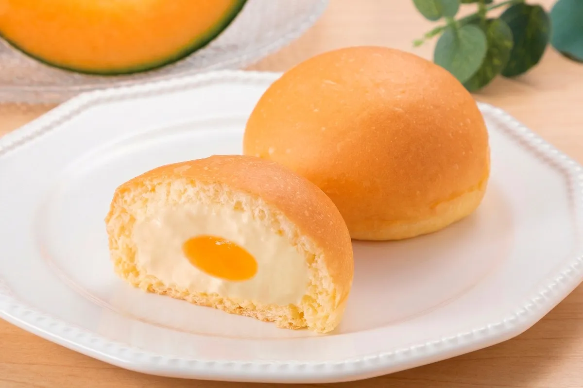 半分に割ったくりーむパンから溢れるオレンジ色のメロンフィリングとクリーム