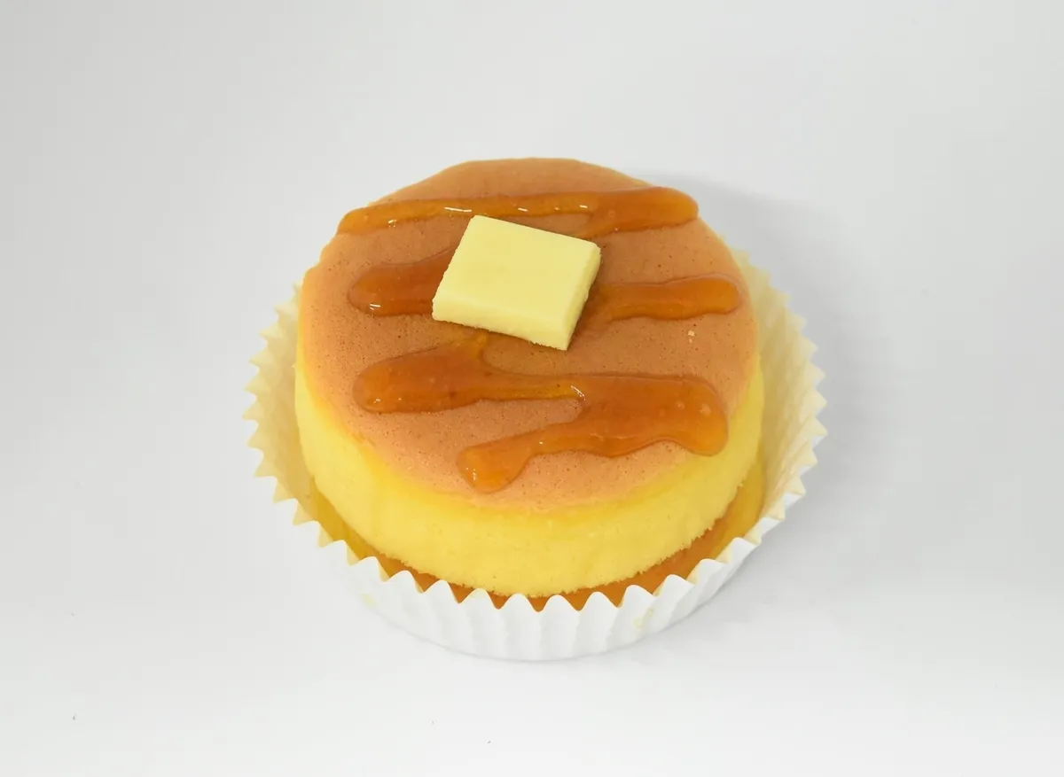 厚みのある生地にメープルソースと角切りバターが乗ったホットケーキのアップ