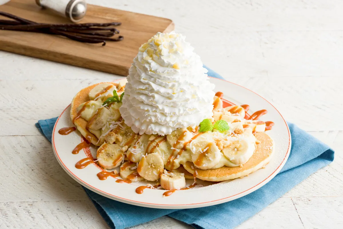 山盛りのホイップクリームとたっぷりのバナナが添えられた塩バニラパンケーキ