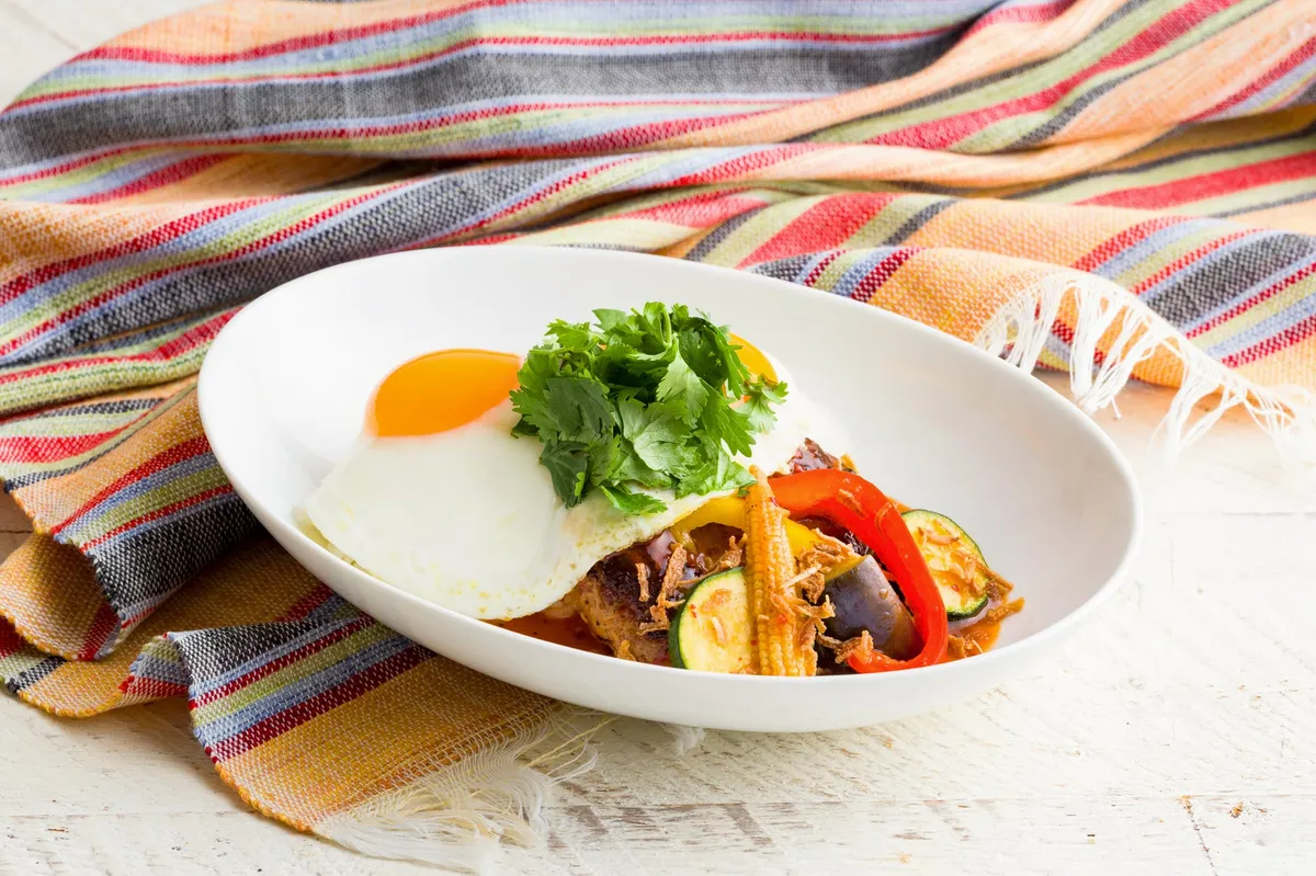 彩り豊かな夏野菜と目玉焼きが乗ったボリューム満点のエスニックロコ・モコ