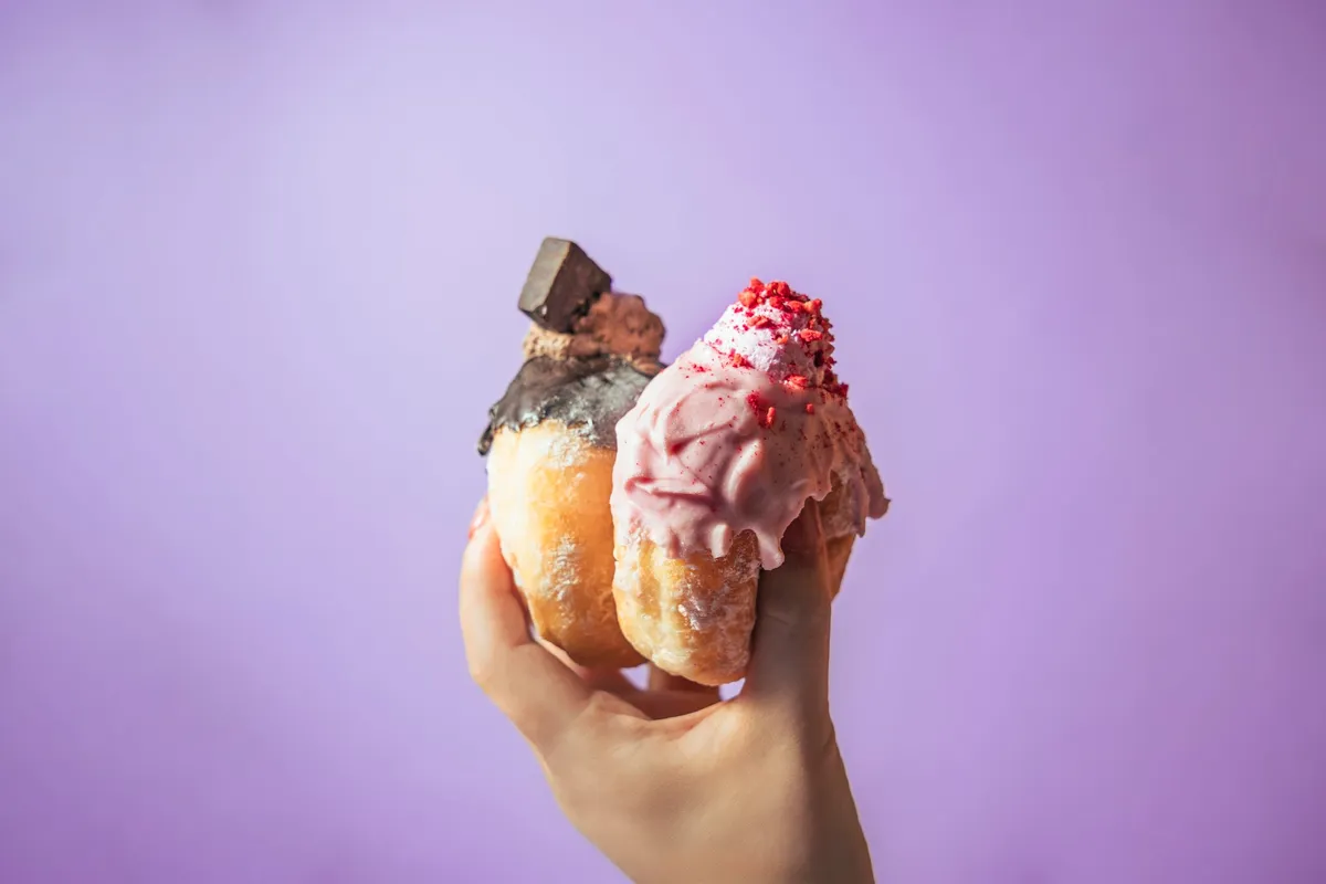 手に持ったカラフルでふわふわな生ドーナツ